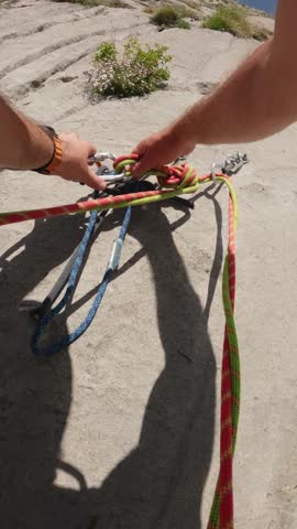 A first person slow motion view of a climber organizing ropes and carabiners at a belay stance on Pic de l Aiguille East Face