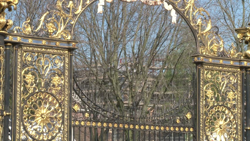 Traffic passing magnificent gold plated park gates.