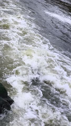 A large body of water with white foam on the rocks.