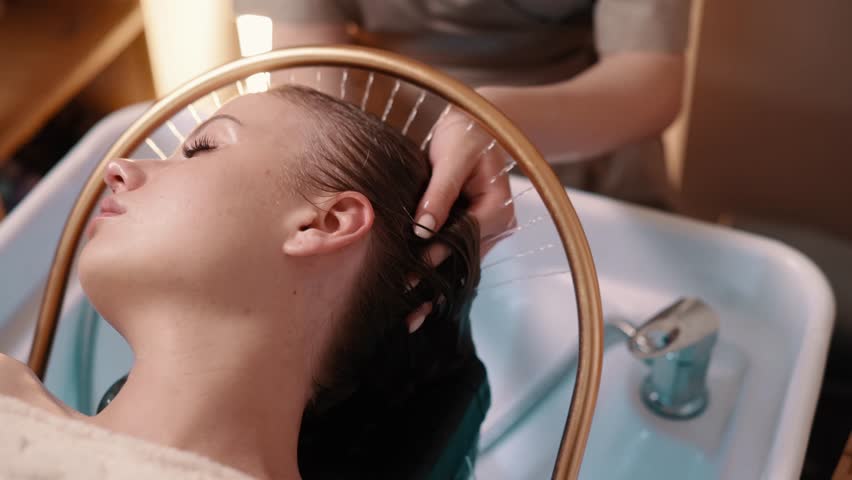 Young woman receiving a head massage during a Japanese head spa treatment with water flowing from a special hair washing tool.