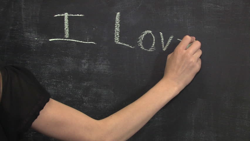 A child writes I Love Mommy on the chalkboard.