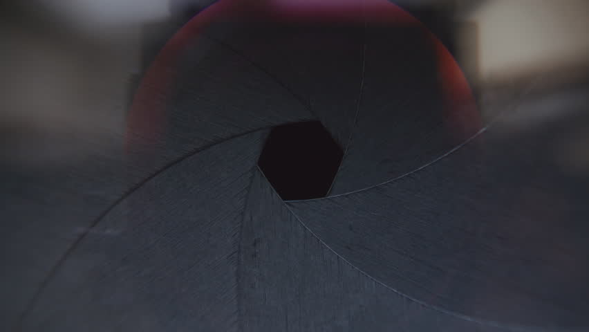 Macro view of overlapping blades snapping open and shut, showing work of aperture diaphragm in camera lens mechanism