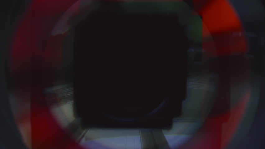 Extreme close-up shot of symmetrical aperture blades closing and forming small central opening in camera lens with colorful light reflections