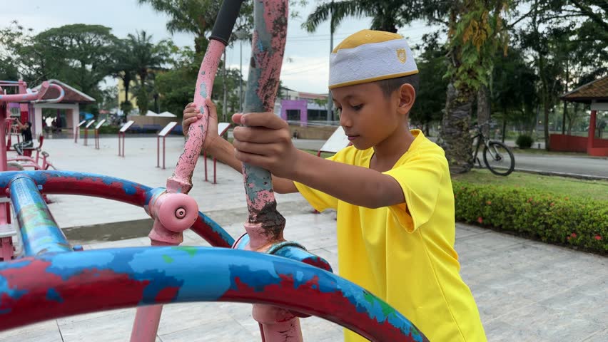Boy in yellow shirt playing on painted playground equipment outdoors.