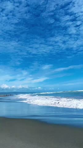 "Waves Crashing on Shore Under Blue Sky with Scattered Clouds, Coastal Seascape"