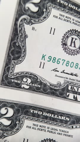 Rolled uncut two dollar bills isolated on white background. A rolled up sheet of uncut two-dollar banknotes isolated on a clean white background.