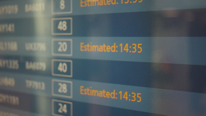 A close-up of a flight information monitor showing arrival and departure times, statuses, and estimated times. The digital display provides essential information for travelers at an airport.