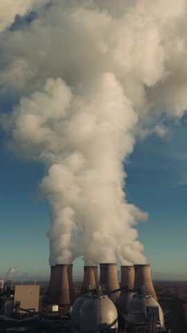 aerial reveal of tall plumes of smoke and steam from a power plant or factory in an air pollution concept video