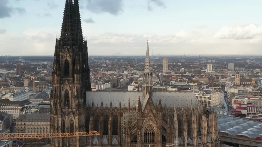 Backwards reveal aerial view of the Cathedral Church of Saint Peter in Cologne, Germany, showcasing the historic Gothic Christian landmark.