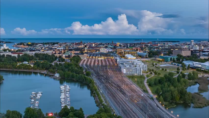 Forwards flyover of Helsinki’s main train station at dusk, showing city centre landmarks and transport infrastructure in the Finnish capital.