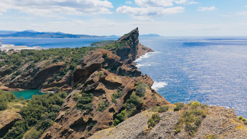 Natural rocky coastline with steep cliffs and coastal erosion patterns along the Mediterranean Sea in southern France. Aerial view