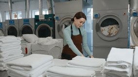 Female worker is carefully folding clean towels in a bustling laundromat - Powered by Shutterstock - Get 15% off with code: PIKWIZARD15