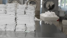 A stack of clean towels on a table in front of a washing machine - Powered by Shutterstock - Get 15% off with code: PIKWIZARD15