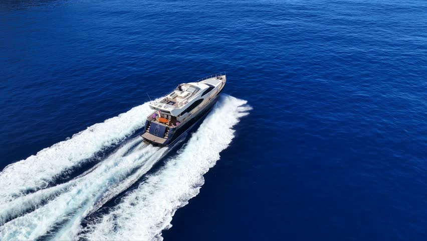 Aerial drone tracking video of luxury yacht cruising in deep blue sea of Mykonos island, Cyclades, Greece