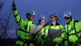 Engineers wearing safety helmets and jackets inspecting a wind turbine at wind farm at dusk. Concept renewable energy, sustainable technology wind power maintenance and environmental engineering. - Powered by Shutterstock - Get 15% off with code: PIKWIZARD15
