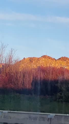 sunset construction site with crane and unfinished apartments, embankment and lamppost in foreground, warm golden light on brick facade,