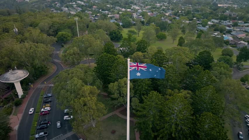 Scenic elevated sunset views of the Australia flag on display at the Picnic Point public park area in Toowoomba with Table Top Mountain and the Bushland Reserve in the background, Queensland, Australia