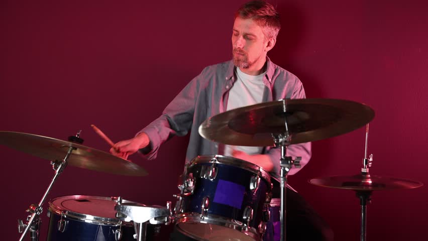 Man playing drums with drumsticks in studio