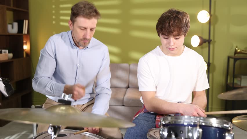 Tutor teaching boy to play drums indoors