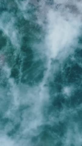 Vertical aerial view of powerful churning turquoise blue whitewater rapids and foam creating an abstract nature texture