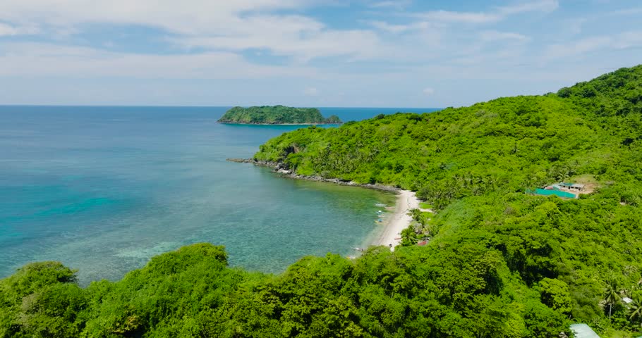 Island with beach, waves on rocks in shoreline. El Nido, Palawan. Philippines.