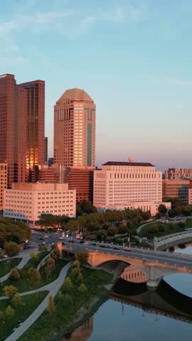 Columbus Ohio skyline at sunset with golden light reflecting on downtown buildings and Scioto river bridge
