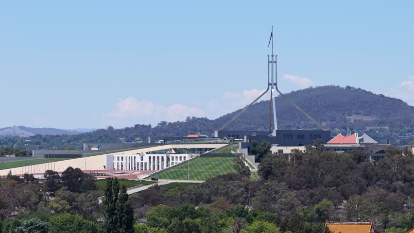 Static wide shot of the Australian Parliament House under a clear blue sky in Canberra