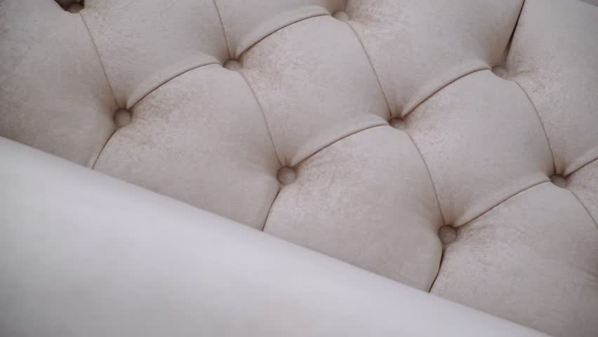 Detail of upholstery of modern furniture, chair, armchair, cushion, pillow. Carriage coupler. Premium luxury fabric. Details of furniture. Design interior. Beige light pink, neutral color backdrop.