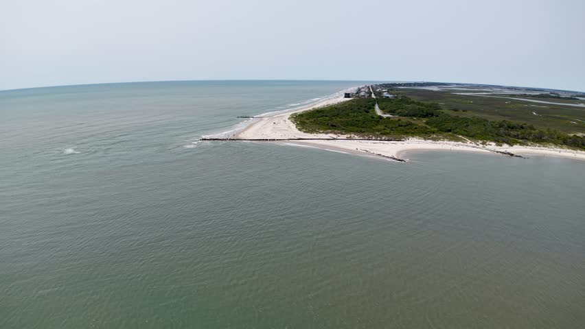 Aerial drone footage capturing a narrow sandy spit along the Charleston coastline of South Carolina, with green vegetation on one side and calm Atlantic waters on both sides.