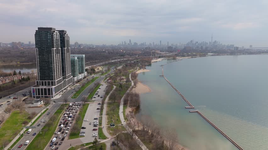 Aerial view of Parklawn condo towers on Lake Ontario with downtown Toronto skyline in the distance, showing Gardner Expressway and Lake Shore Boulevard traffic.