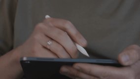 Close up shot from a front angle shows a creative professional drawing on a graphic tablet with a stylus. Camera focuses on hand interaction and calm, focused digital creativity. High quality 4k - Powered by Shutterstock - Get 15% off with code: PIKWIZARD15