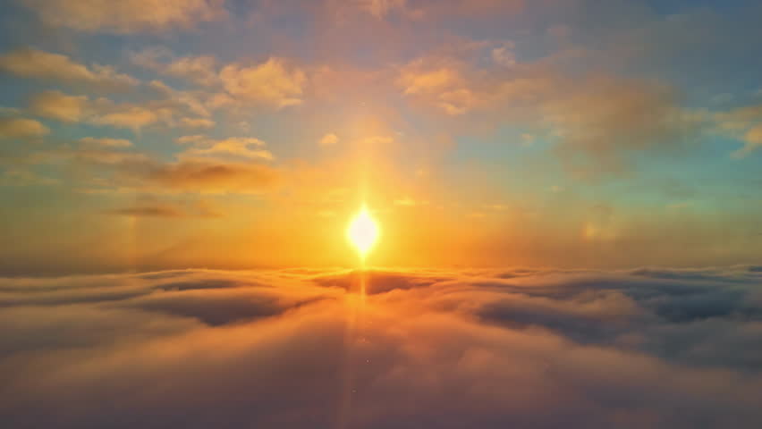 Golden sunrise above a cloud layer with bright snow sparkles drifting in the air, creating a warm atmospheric aerial moment.