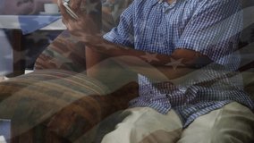 A senior man is using a mobile phone with his friends sitting in the background at a retirement home. Global business data processing and technology concept digitally generated video. - Powered by Shutterstock - Get 15% off with code: PIKWIZARD15