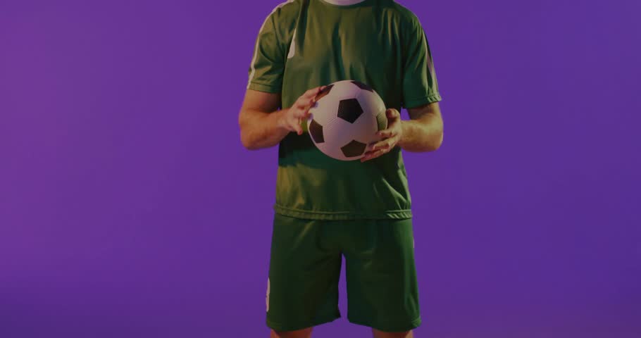 Balancing soccer ball, man in green jersey with purple smoke and lights around. Sports, athlete, football, dynamic, energy, vibrant