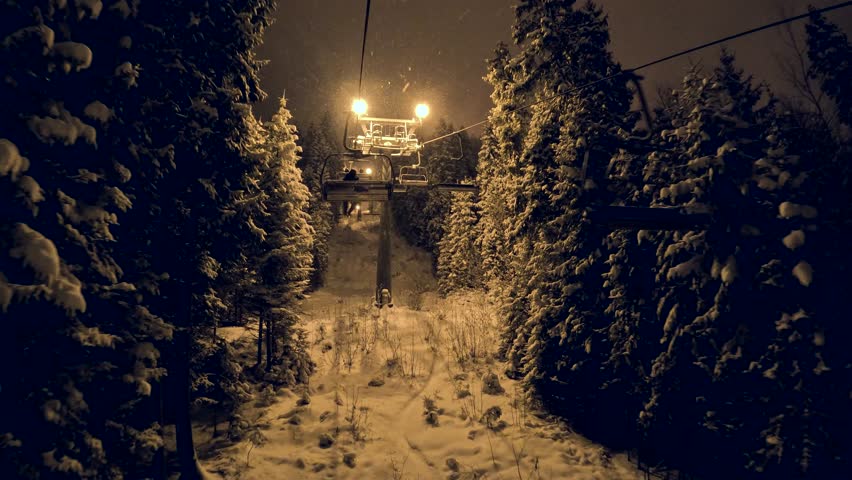 Night ski lift ride in snowy forest
