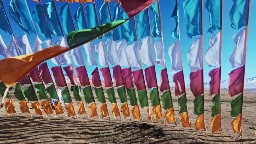 Colorful Tibetan Buddhist Prayer Flags Hanging And Fluttering Against Bright Blue Sky. tilting shot