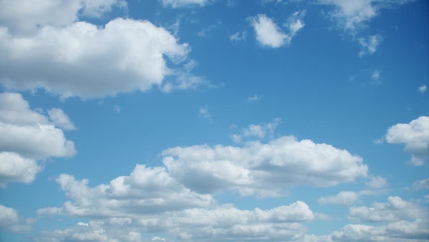 Slowly floating white cumulus clouds. A calm blue sky with fluffy clouds in summer.