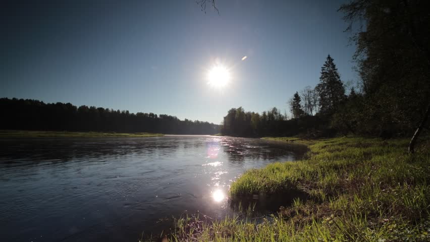 Morning landscape on a foggy river, the sun rises and reflects in the flowing water of the river, the river banks are covered with forest, the landscape is wild