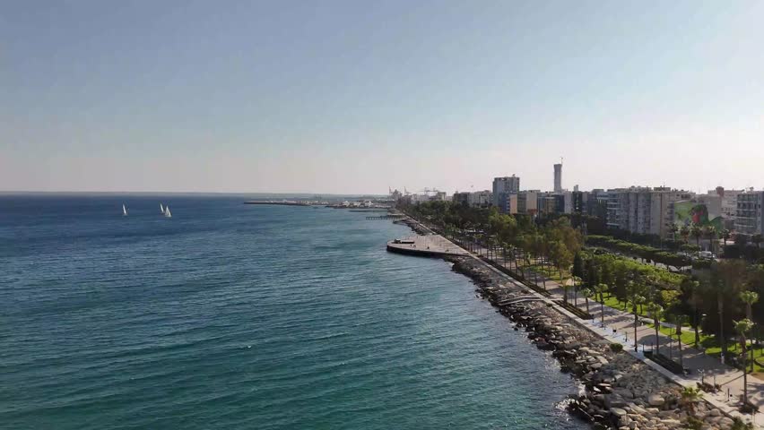 Drone shot of Limassol's vibrant promenade (Molos) with people walking and sandy beaches