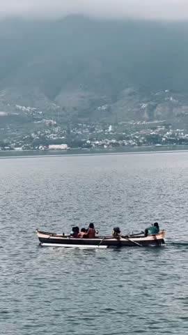 A scenic sea and mountain landscape with a boat passing across the water. Calm ocean and natural surroundings create a peaceful outdoor scene.