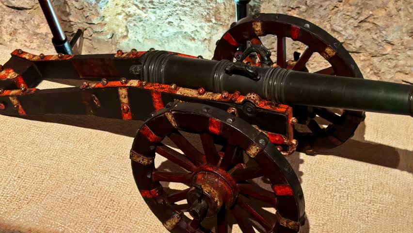 Close-up of an antique cannon on a wooden carriage in a museum gallery, showcasing historic artillery craftsmanship, iron barrel details, and aged patina.