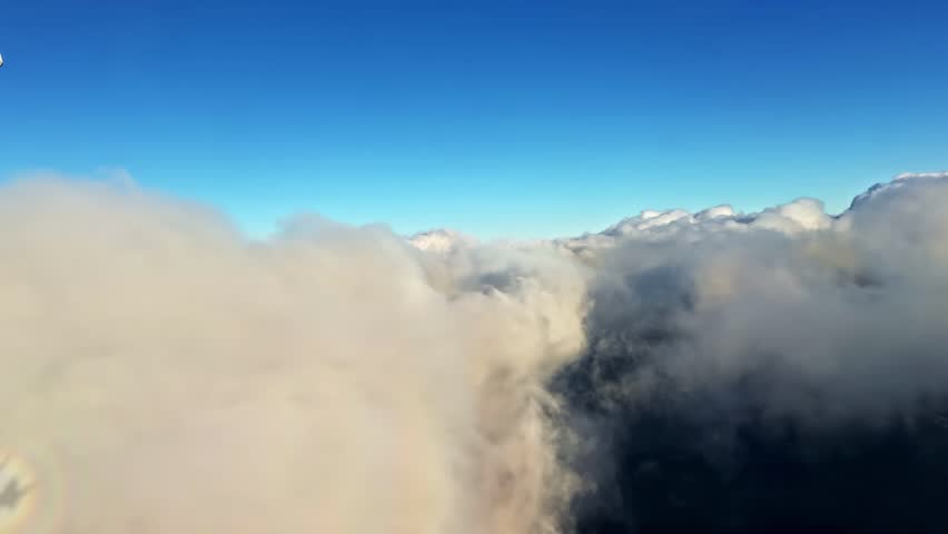 Aerial view of clouds covering mountaintops under clear blue sky, high altitude