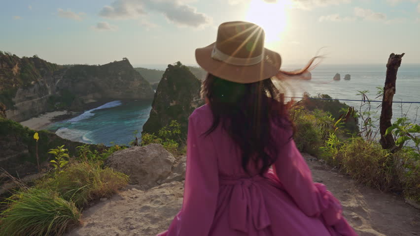 Woman stands at the Diamond Beach viewpoint, watching the sunrise in Indonesia.