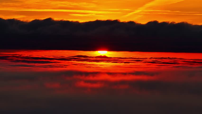 Above clouds Intense sunrise piercing low clouds over sky with deep orange and red tones
