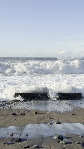 Stormy Waves Crash over Smooth Pebbles on Windy Coastal Shoreline