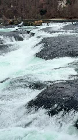 Close-up of powerful Rhine Falls waterfall in winter. Churning white water rapids and mist on the Rhine River near Schaffhausen, Switzerland. 4K nature footage, January 2026.