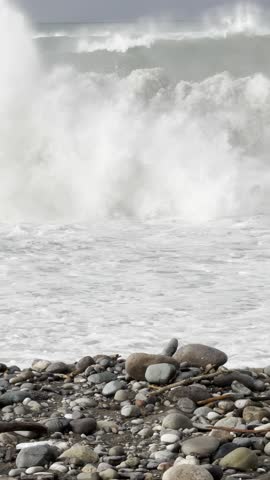 Stormy Waves Crash over Smooth Pebbles on Windy Coastal Shoreline