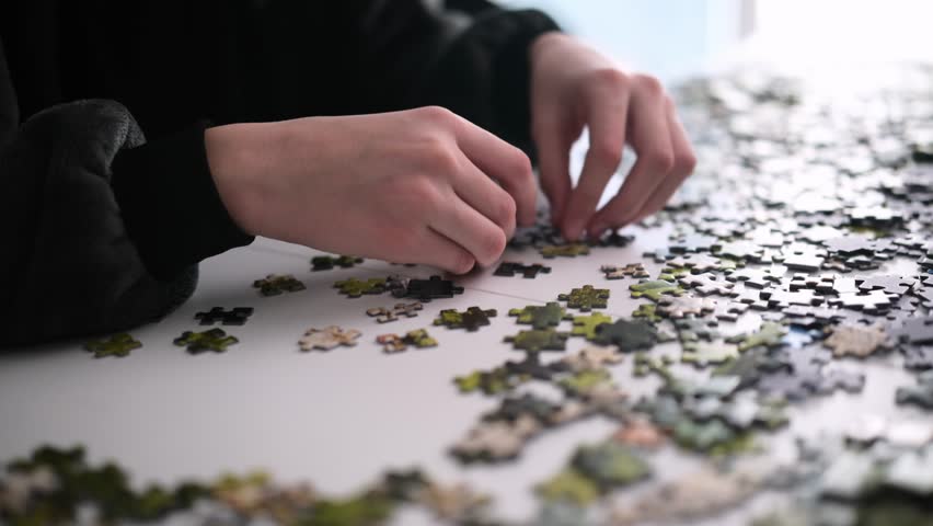 Hand Of A Little Girl Assembling A Puzzle On A Table