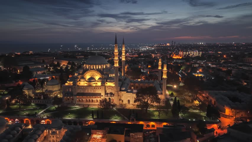 Suleymaniye Mosque illuminated at sunset over historic Istanbul skyline in Turkey, iconic Ottoman landmark glowing in warm evening light near the Golden Horn and Bosphorus. Aerial View