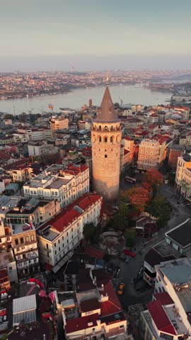 Galata Tower in Istanbul illuminated by rising morning sun, iconic medieval landmark surrounded by historic cityscape and warm golden sunrise light. Aerial View shows calm early city atmosphere